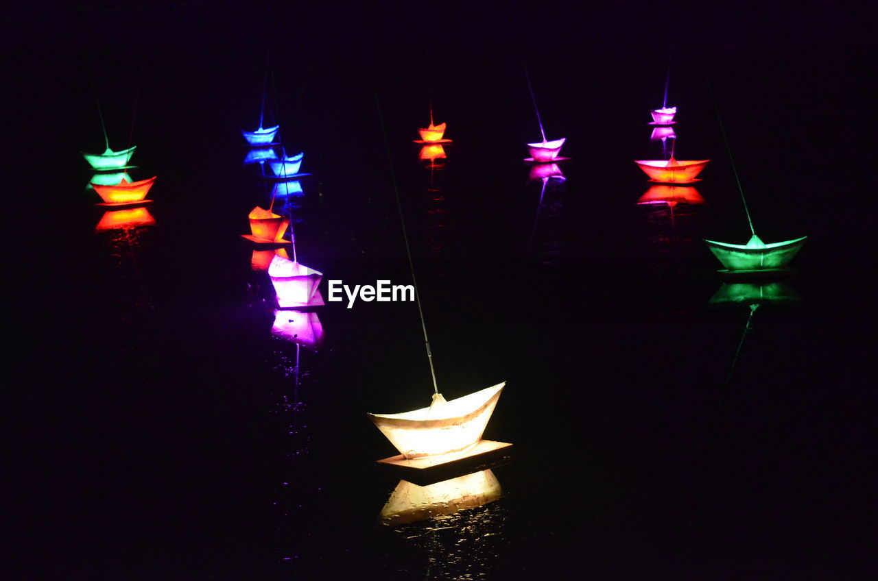 Close-up of illuminated paper boats against black background