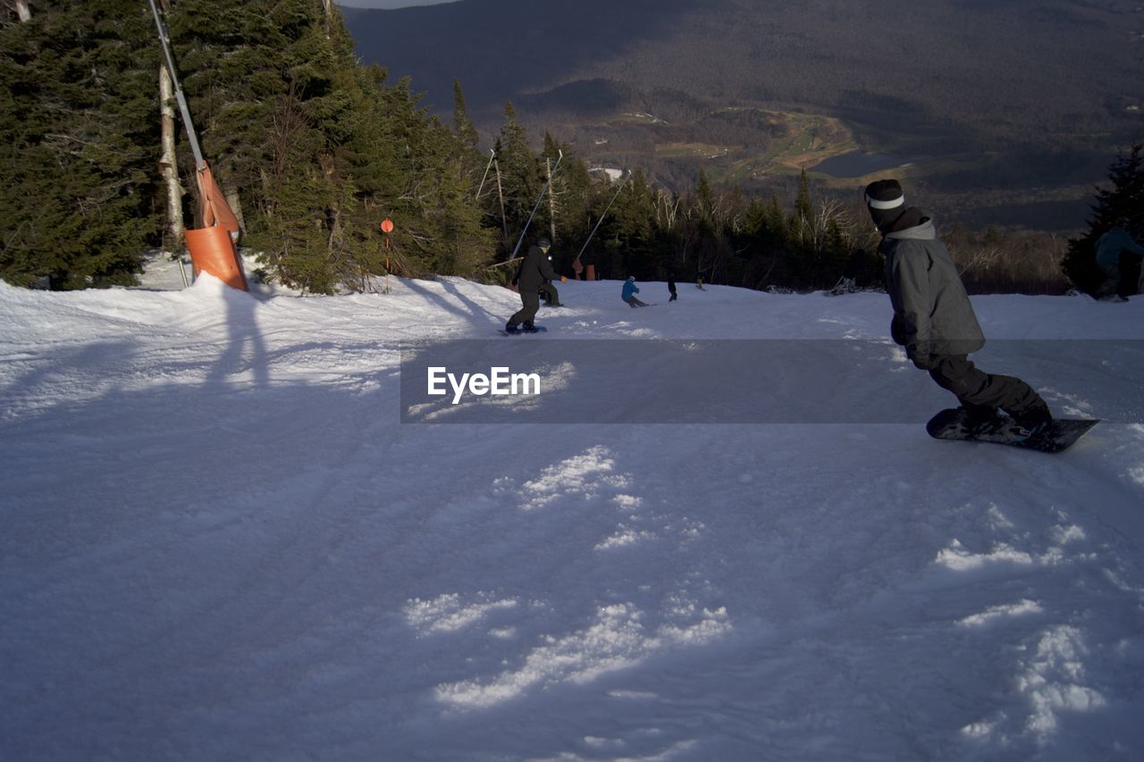 People snowboarding on field during winter