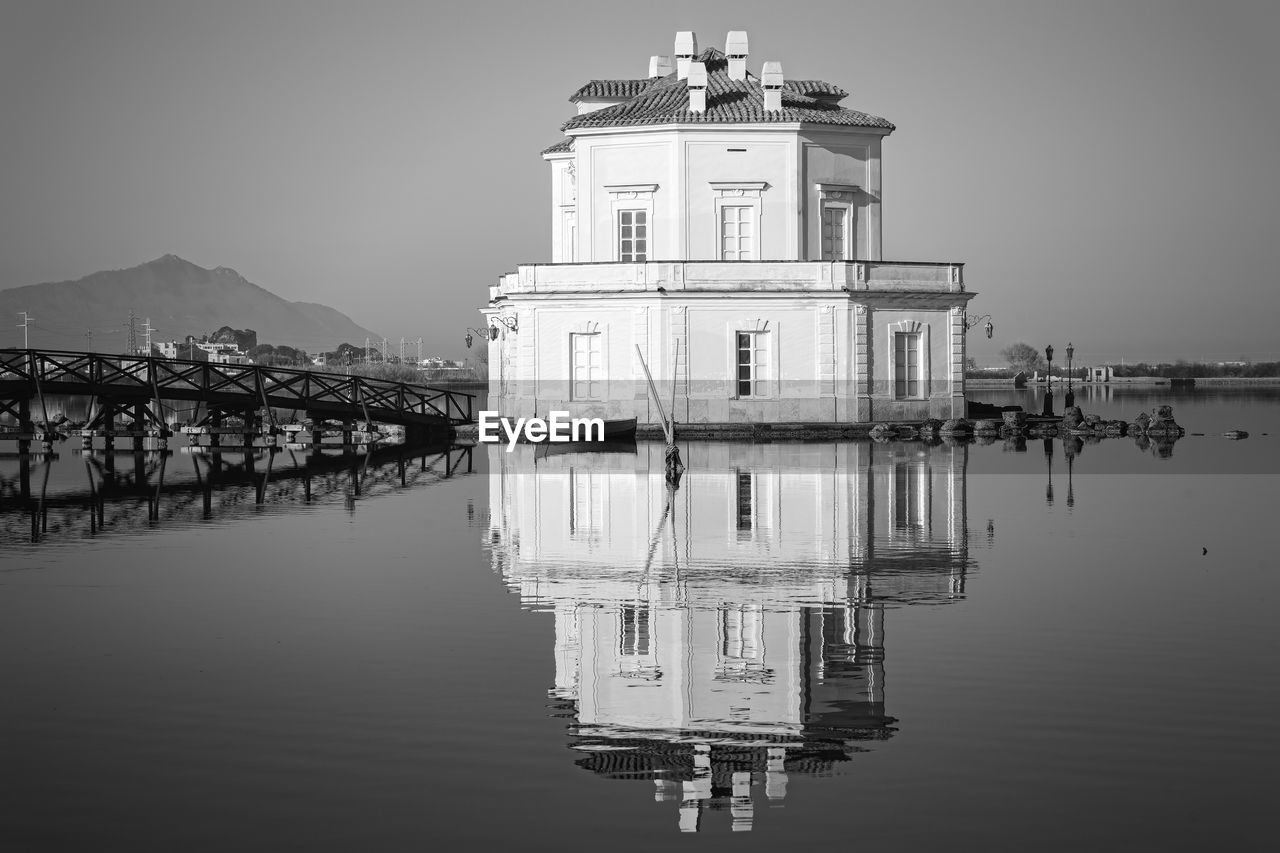Building reflecting on river against clear sky