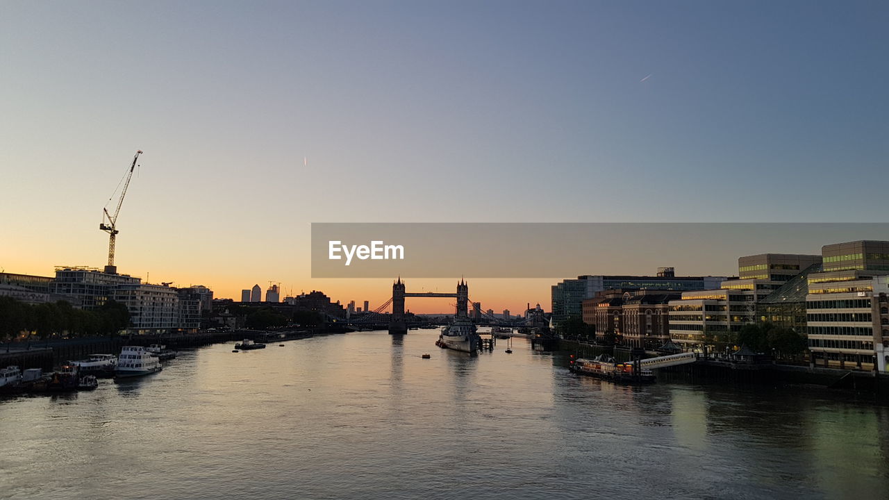 River amidst buildings against sky during sunset