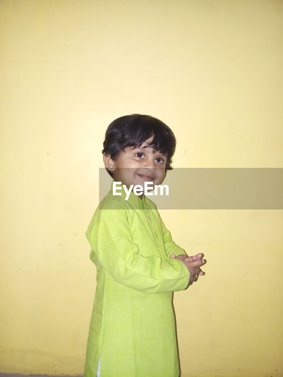 PORTRAIT OF BOY STANDING AGAINST WALL AGAINST YELLOW BACKGROUND