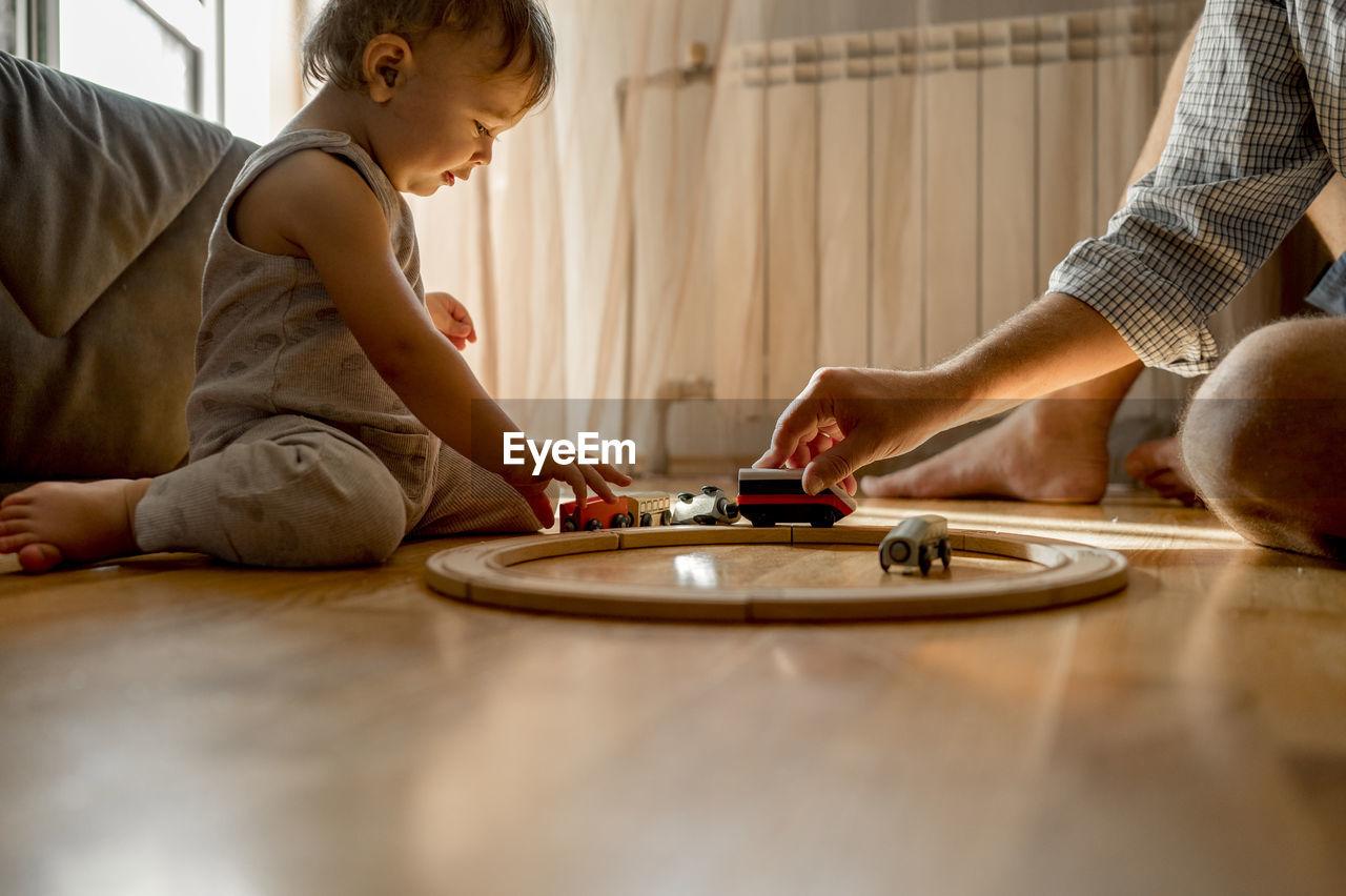 Father and son playing with toy train on floor at home