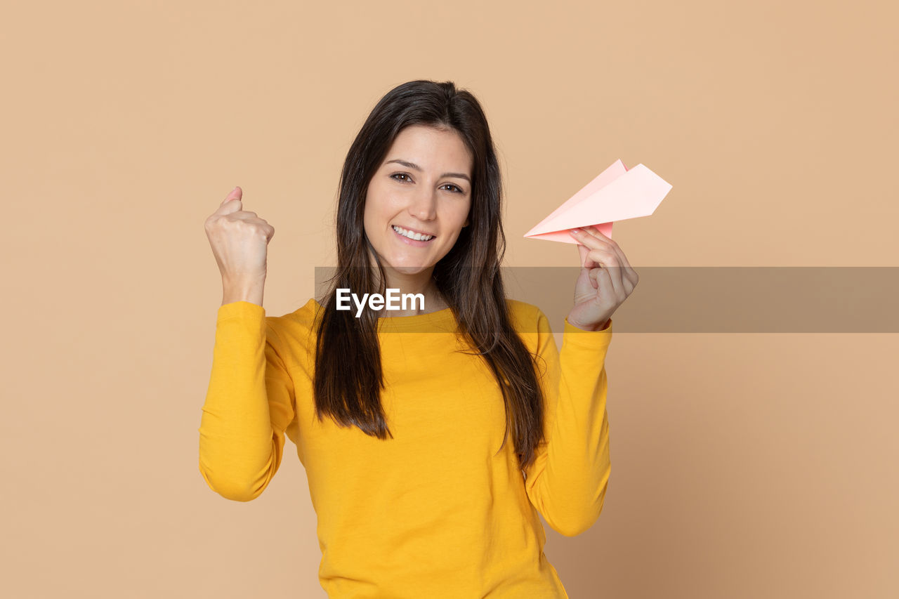 PORTRAIT OF A SMILING YOUNG WOMAN OVER YELLOW BACKGROUND