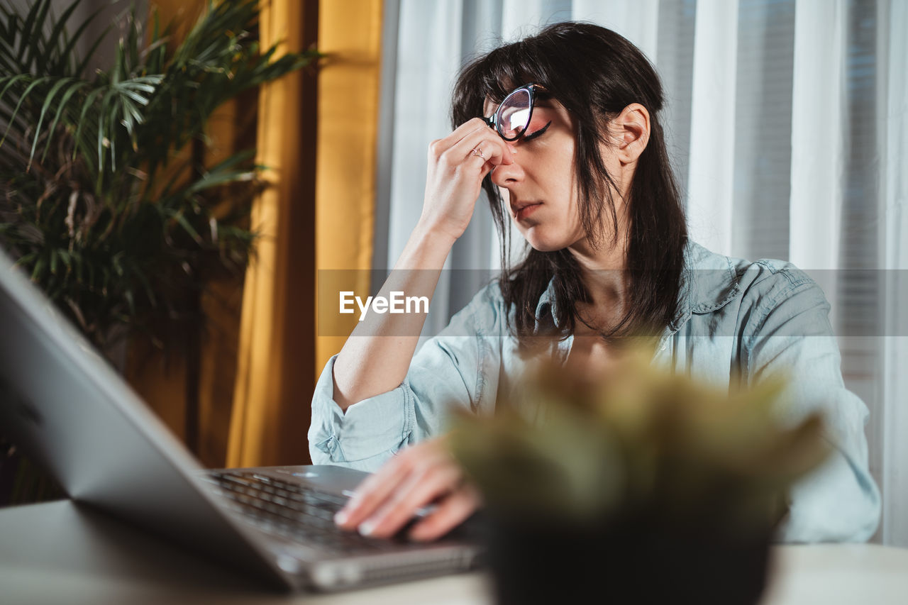 Frustrated young woman by laptop in office