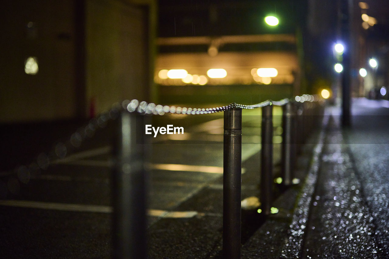 Illuminated railing by street in city at night