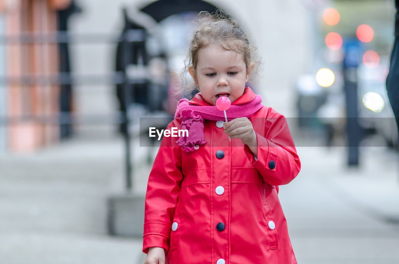 Girl in pink jacket holding lollipop