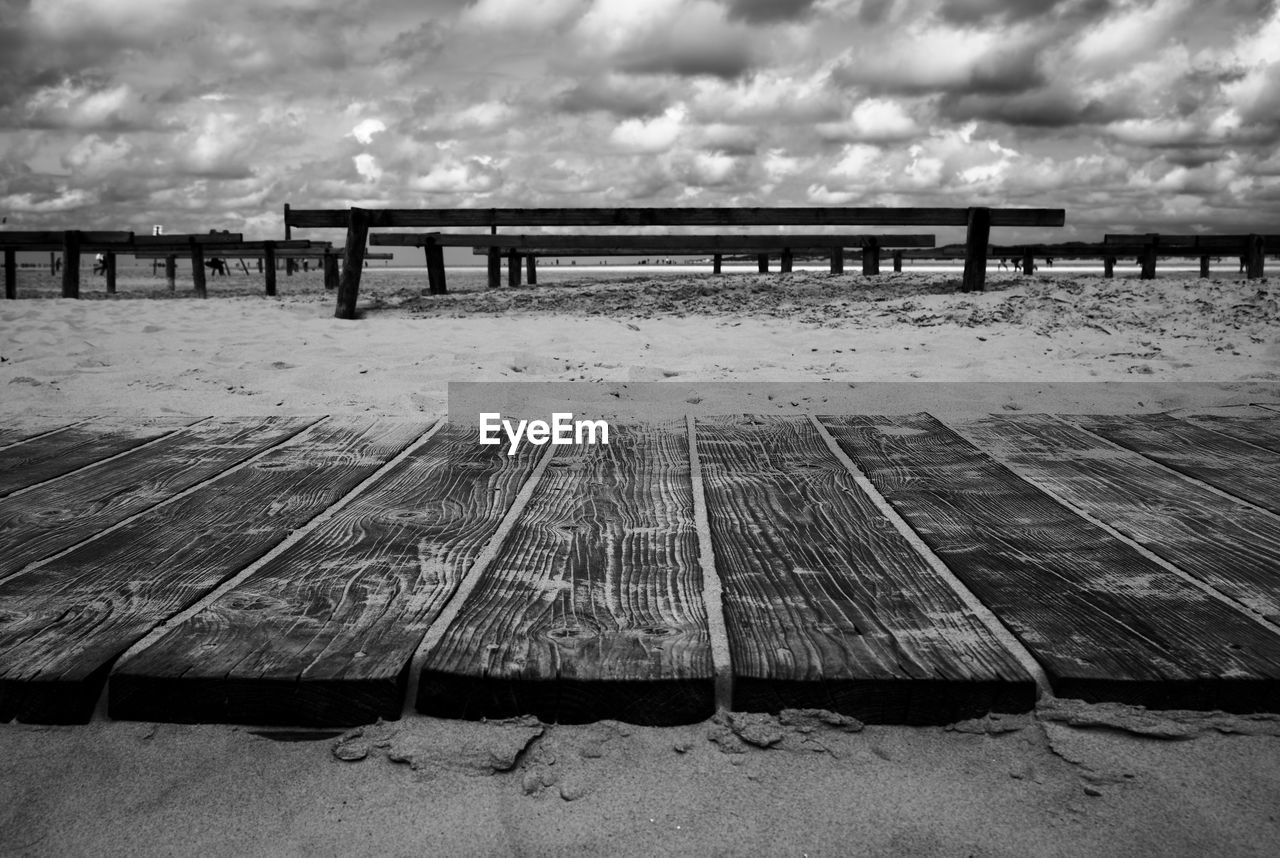 EMPTY BENCHES ON PIER AGAINST SKY