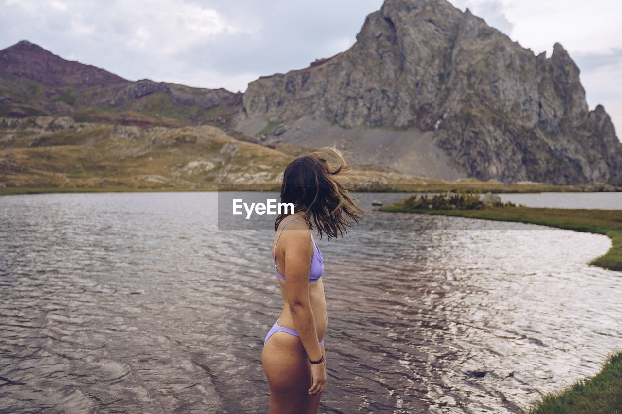 Young woman wearing bikini standing in lake of ibones of anayet
