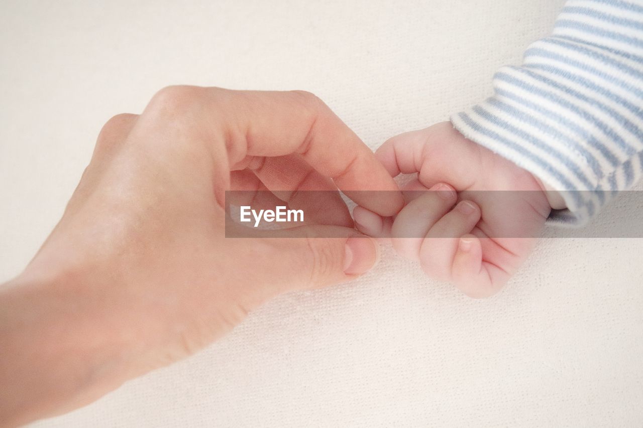 Cropped image of mother holding baby hand