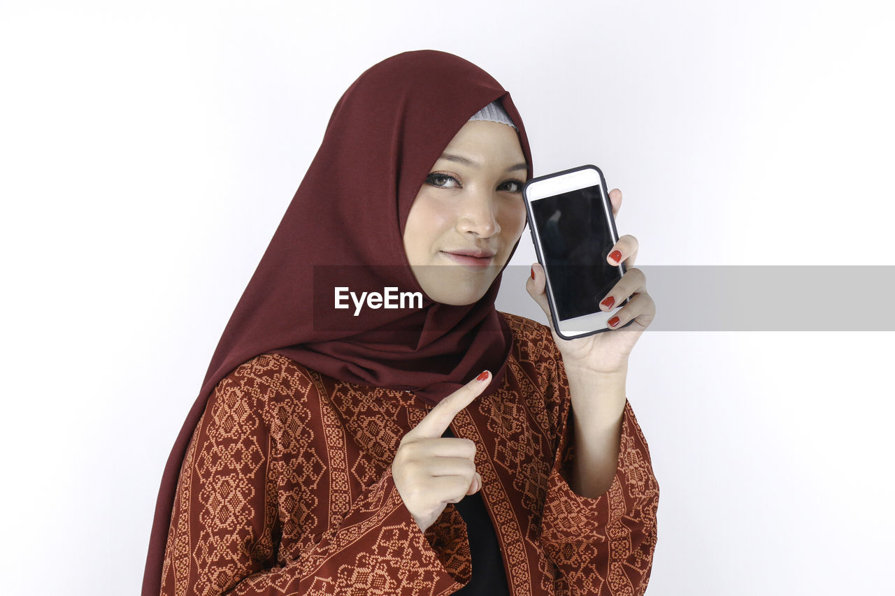 PORTRAIT OF BEAUTIFUL YOUNG WOMAN USING SMART PHONE