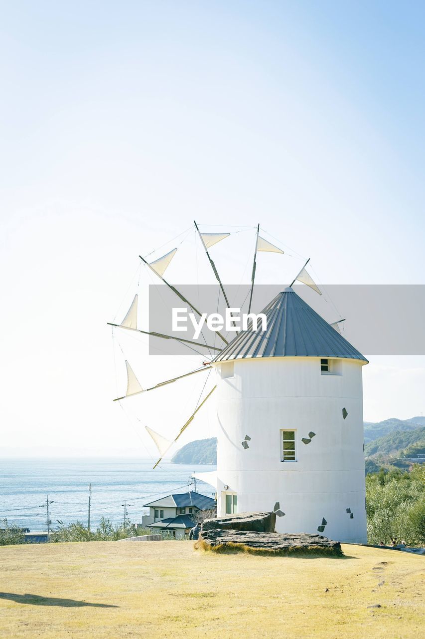 Traditional windmill on beach against clear sky