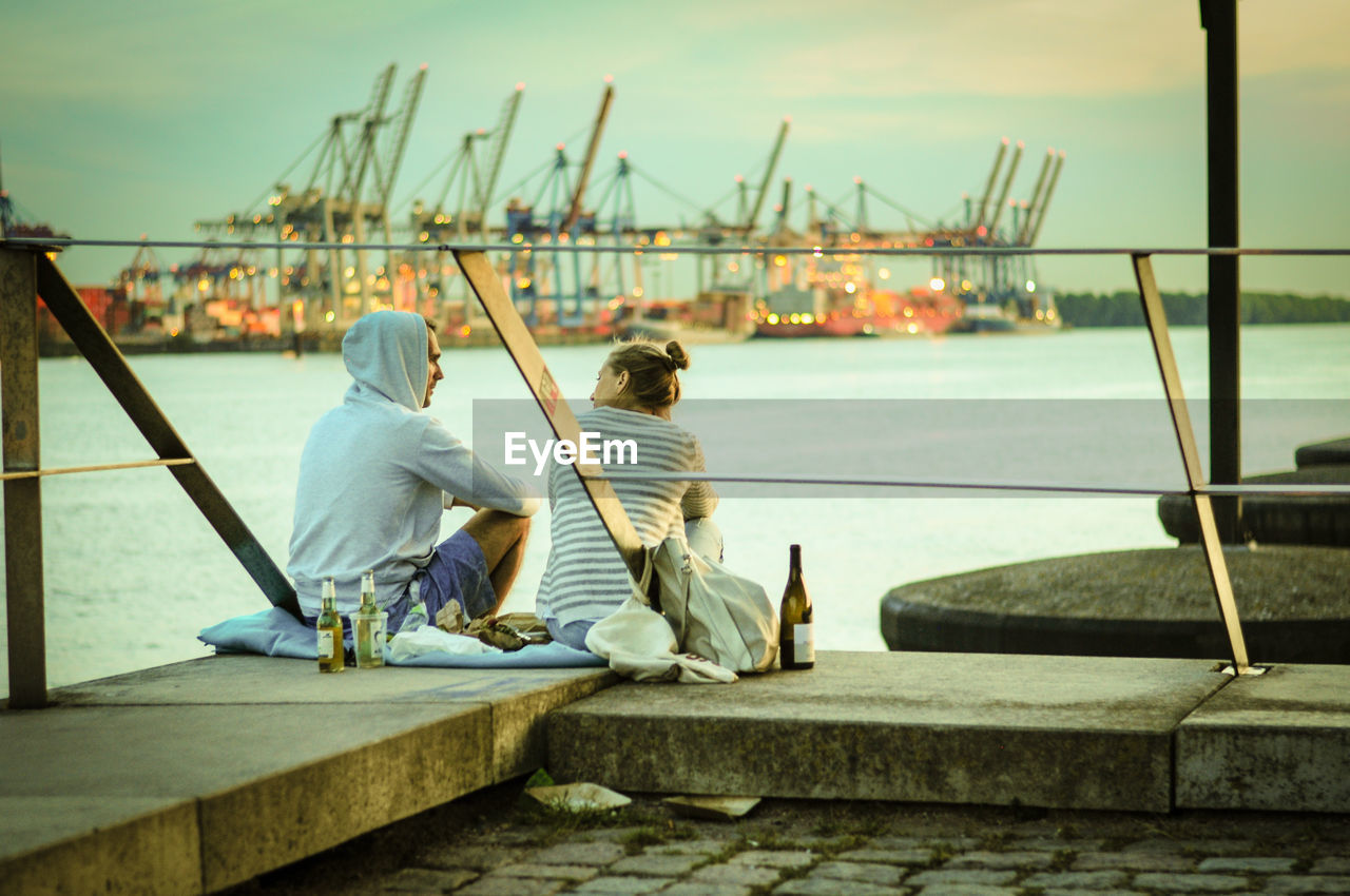 REAR VIEW OF MEN SITTING ON BOAT