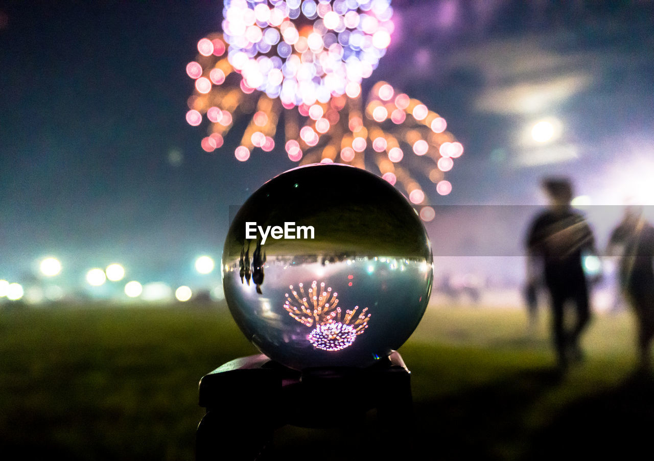 DEFOCUSED IMAGE OF MAN ON ILLUMINATED FIELD AT NIGHT