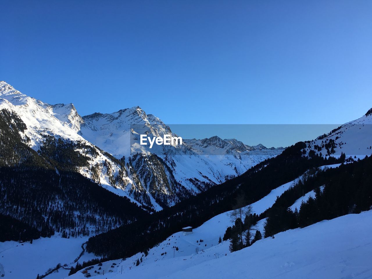 Scenic view of snowcapped mountains against clear blue sky