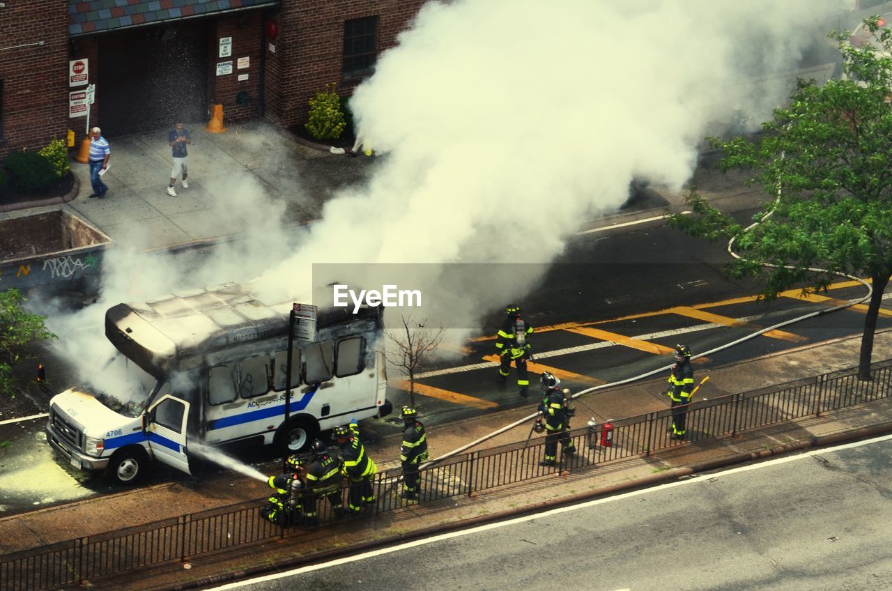 High angle view of firefighters putting out van fire on street