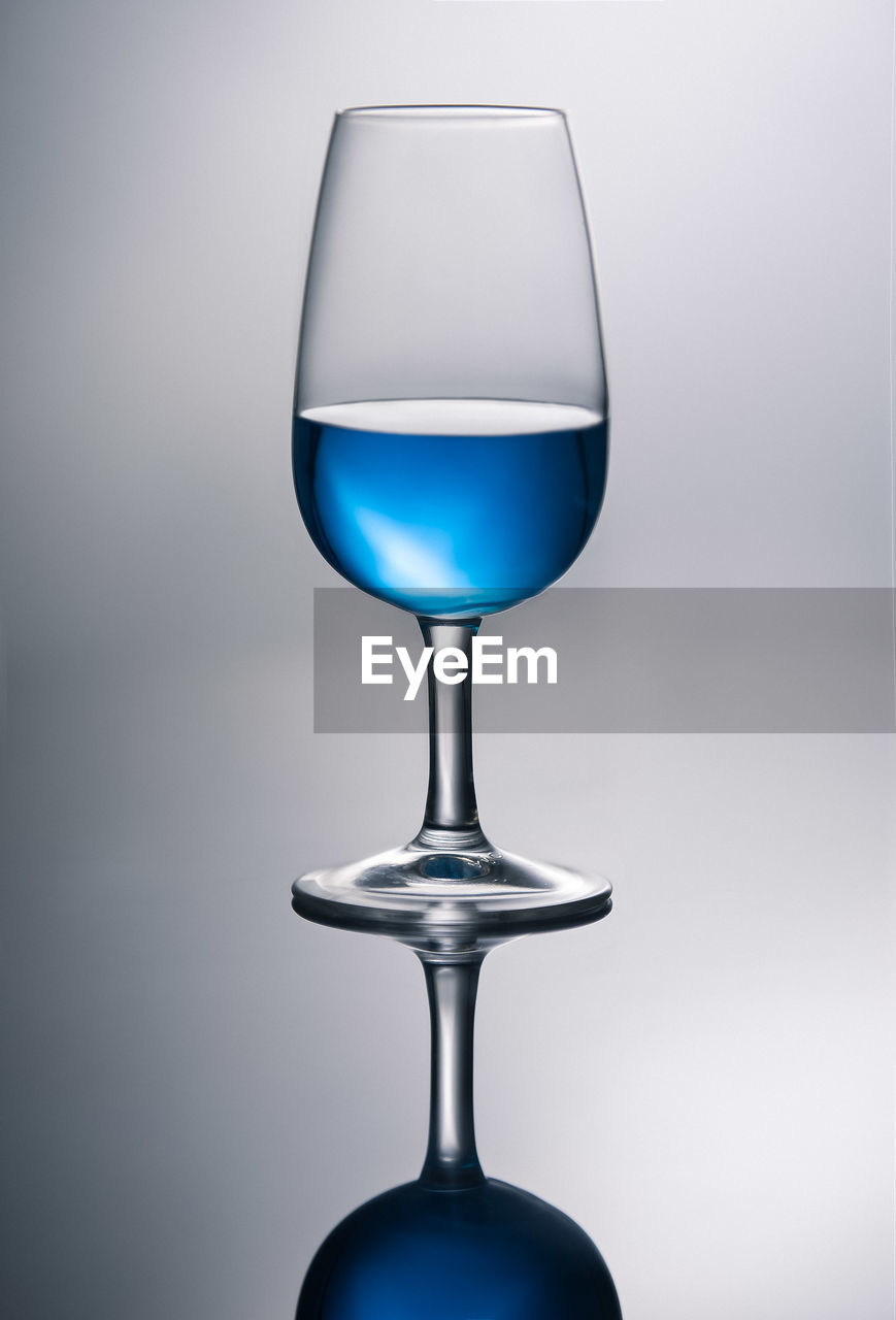 Blue wine in glass against gray background