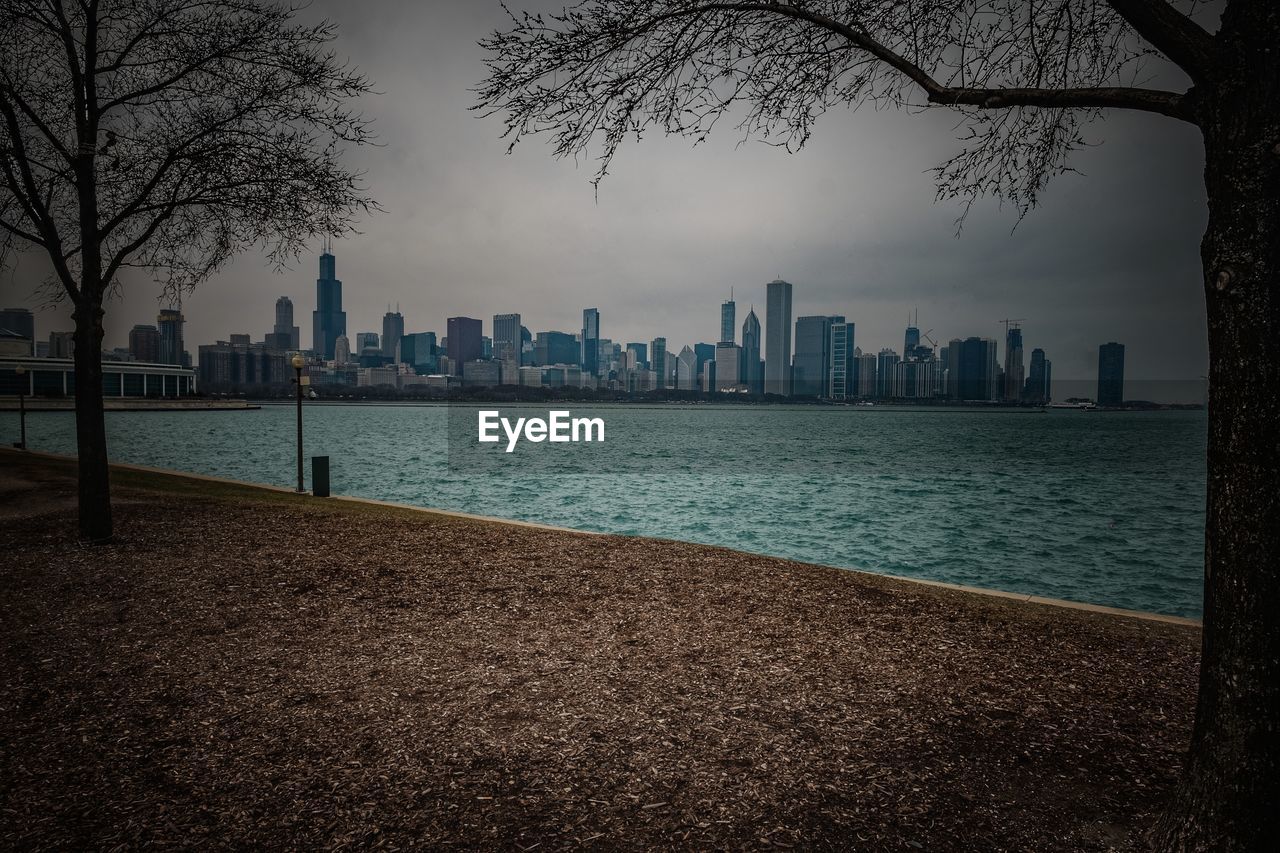 Sea and buildings in city against sky