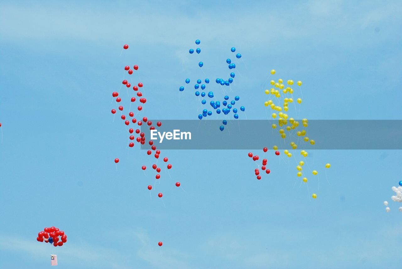 Low angle view of colorful balloons flying against clear sky