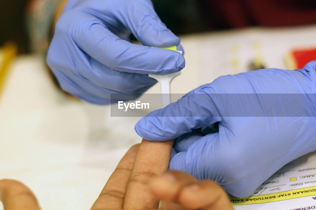 Cropped hands of doctor removing blood sample from patient finger