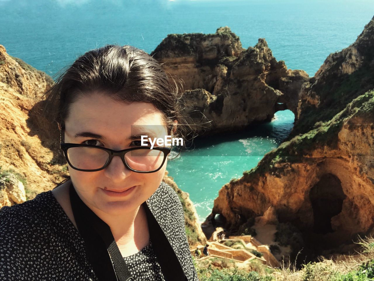 Portrait of young woman standing on hill by sea