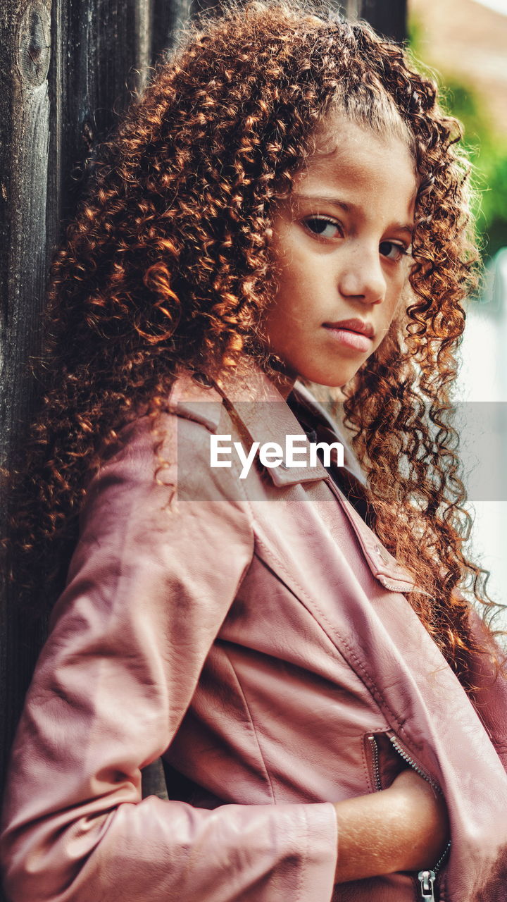 Portrait of girl with curly brown hair standing outdoors