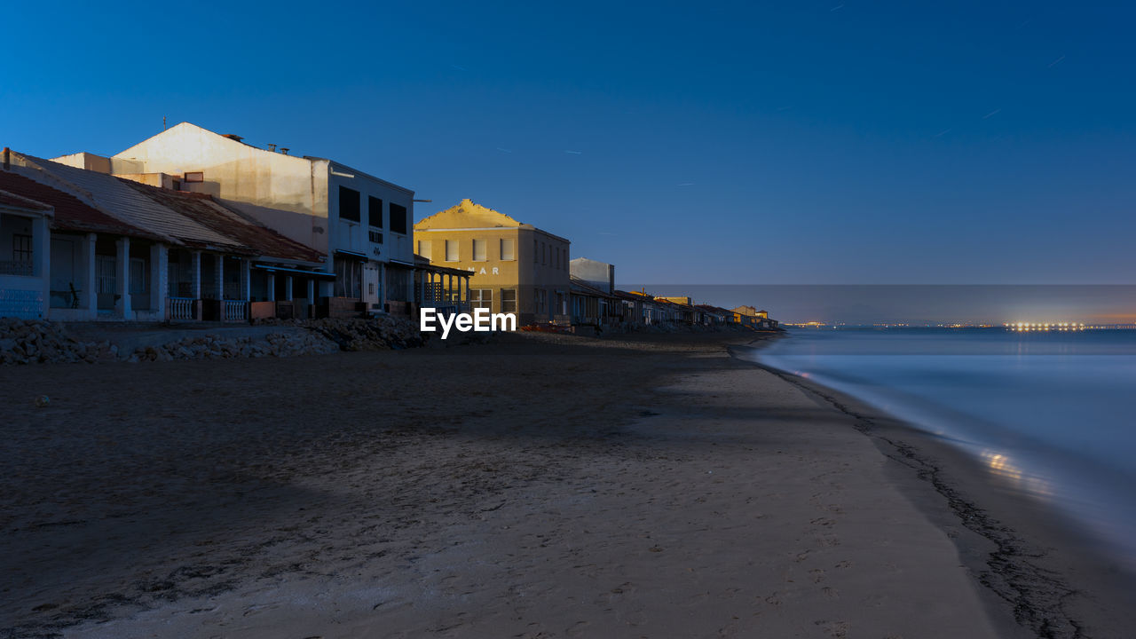 buildings by sea against clear sky at night