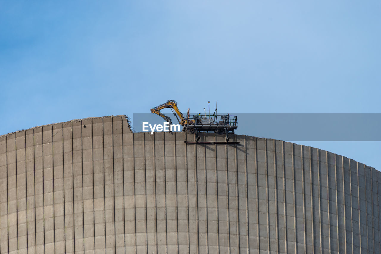 Demolition of the atomic chimney. remote controlled excavator with shears works from above.