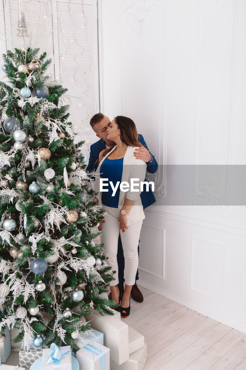 Couple kissing while standing by wall at home