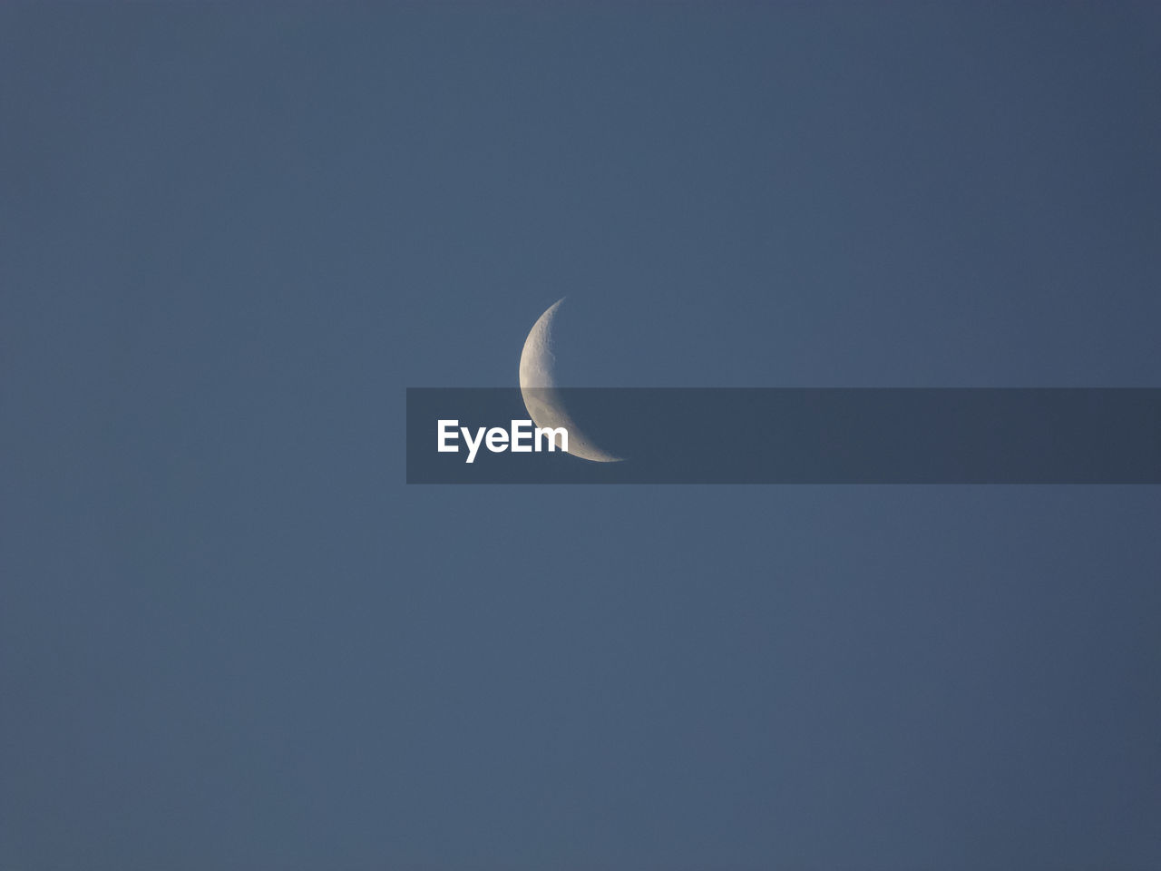 LOW ANGLE VIEW OF HALF MOON AGAINST CLEAR SKY AT NIGHT