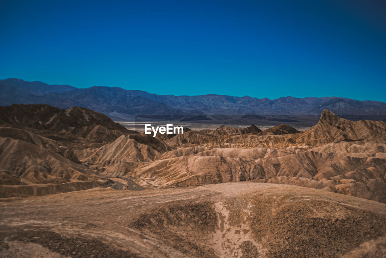 Scenic view of arid landscape against clear blue sky