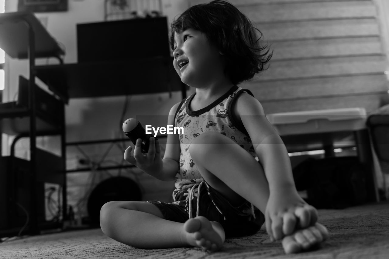 Young boy looking away while sitting on floor at home