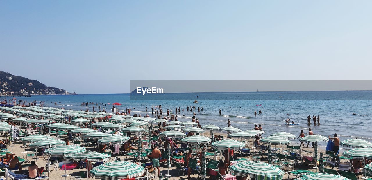 Panoramic view of people on beach against clear sky