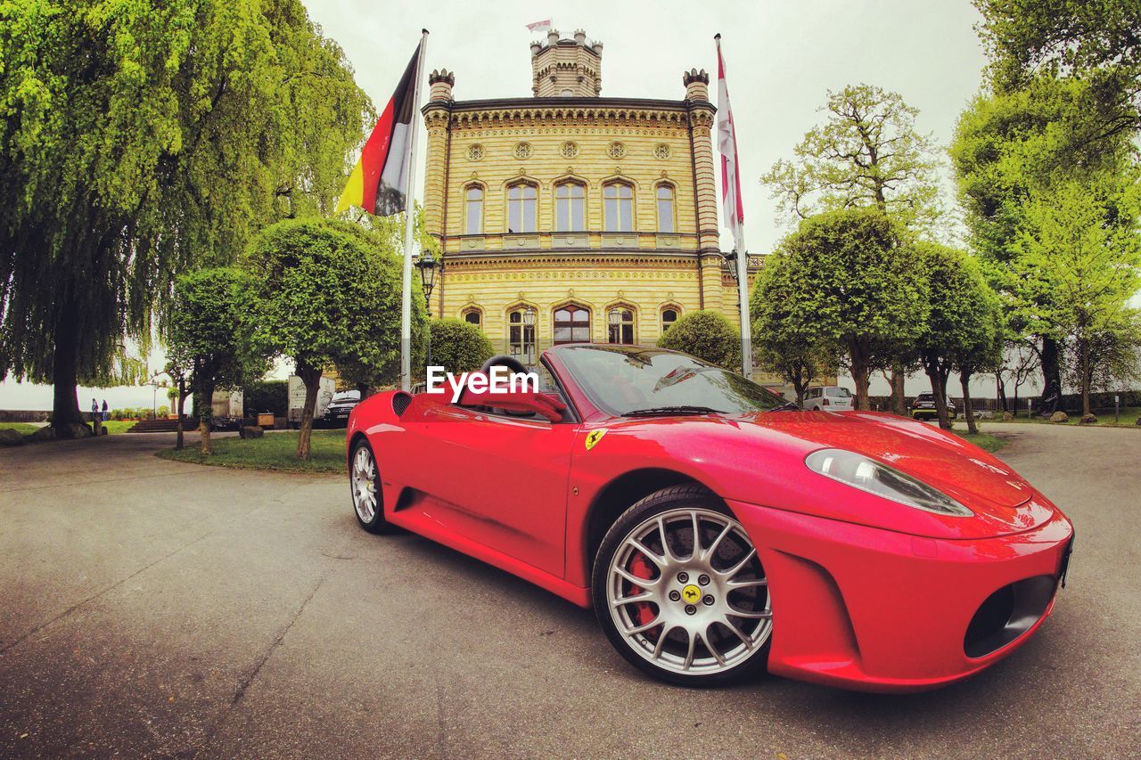 RED CAR ON BUILDING BY CITY