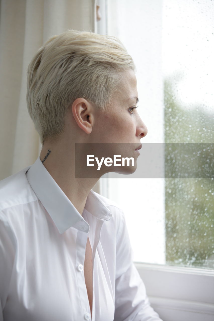 Close-up of woman looking through window at home