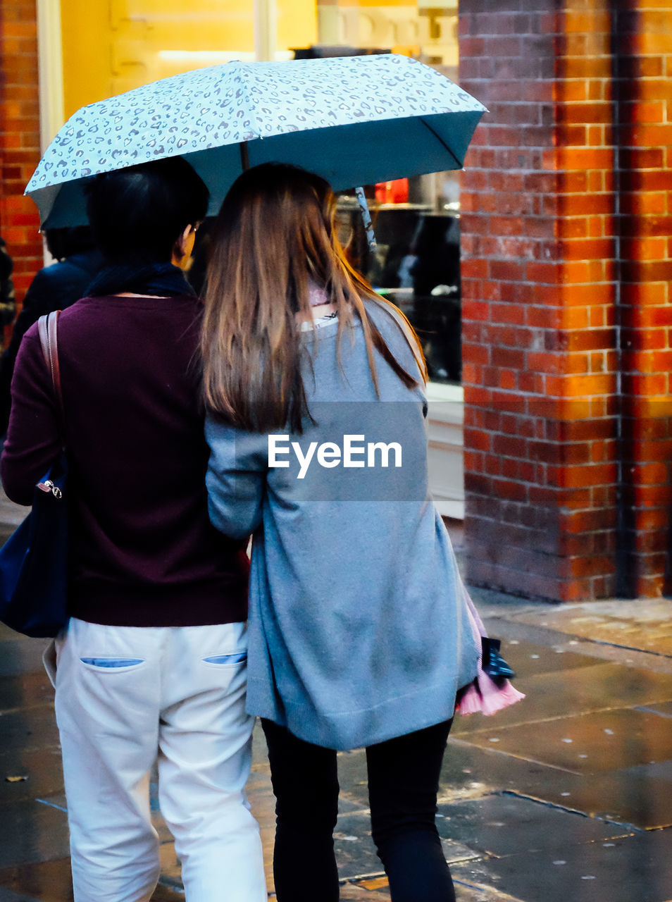 Rear view of women walking on wet street