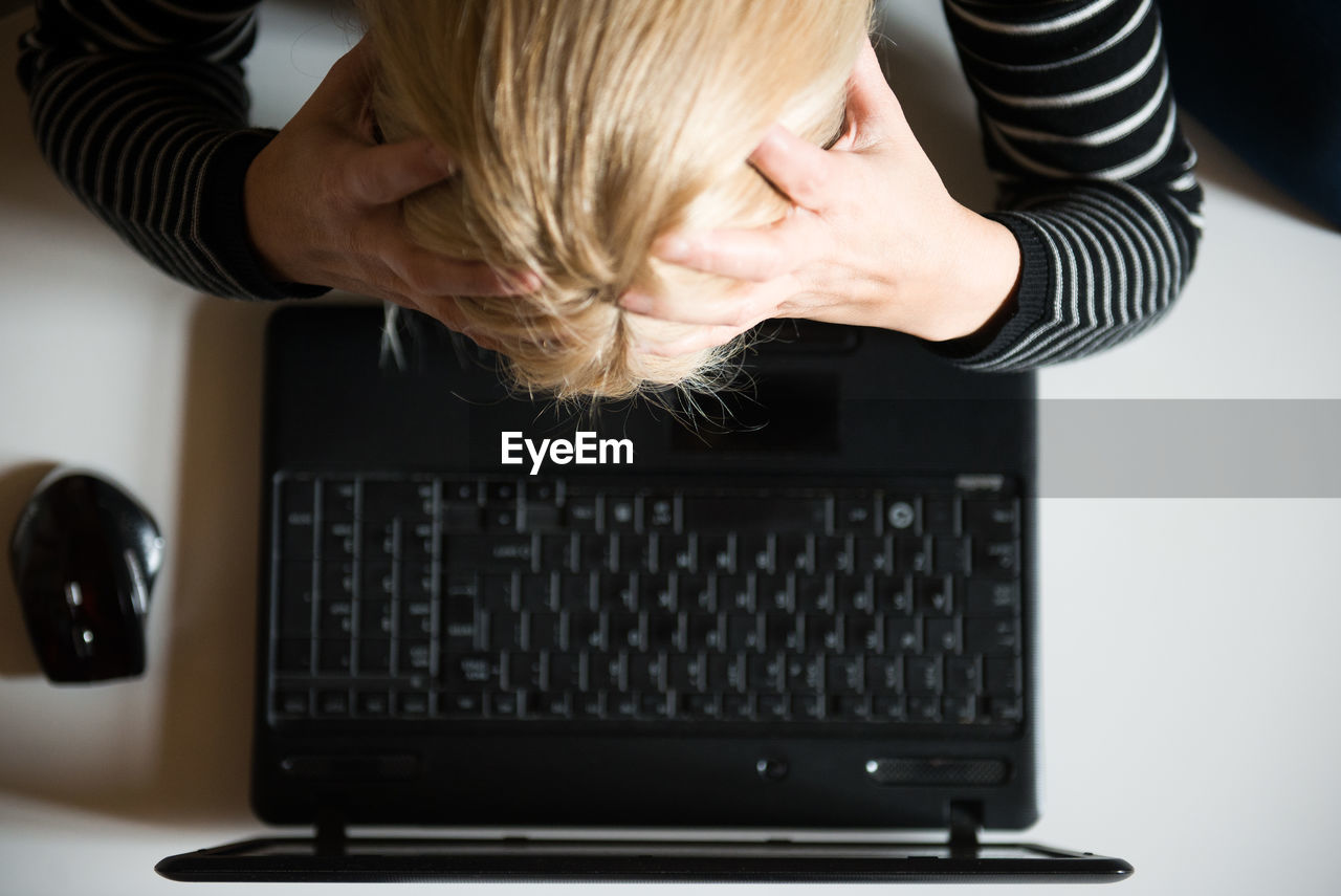 Tensed woman using laptop at desk