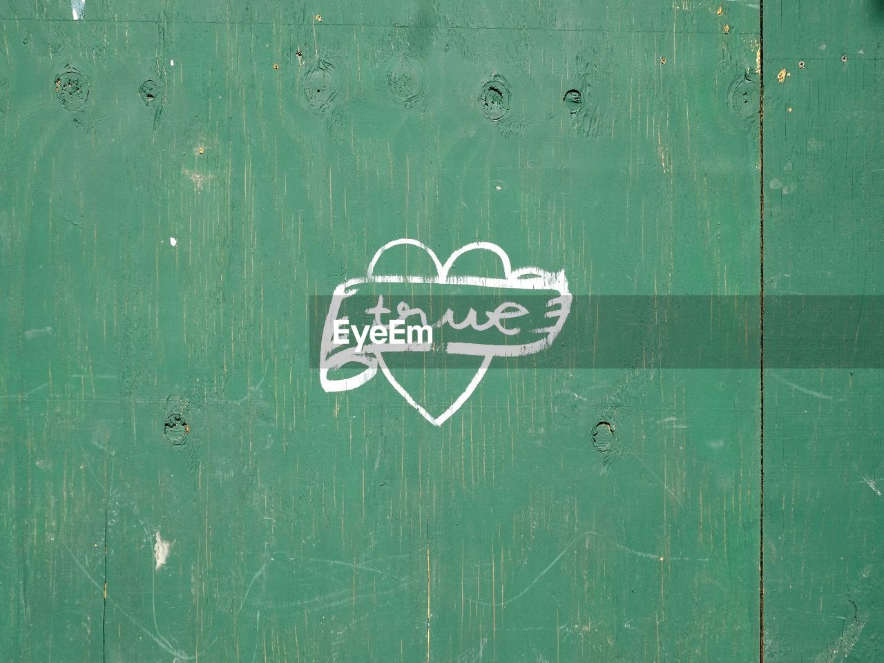 Text with heart shape on green wooden door