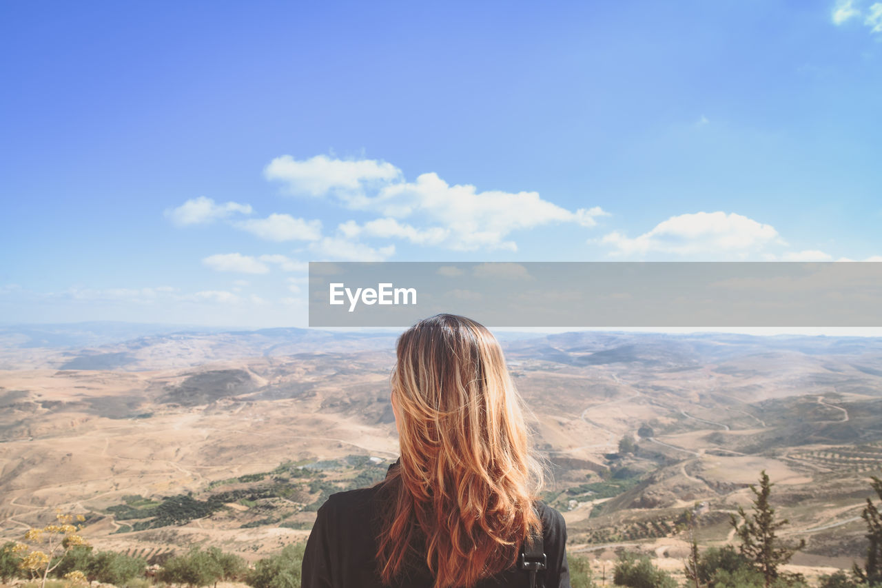 Rear view of woman standing in front of mountains