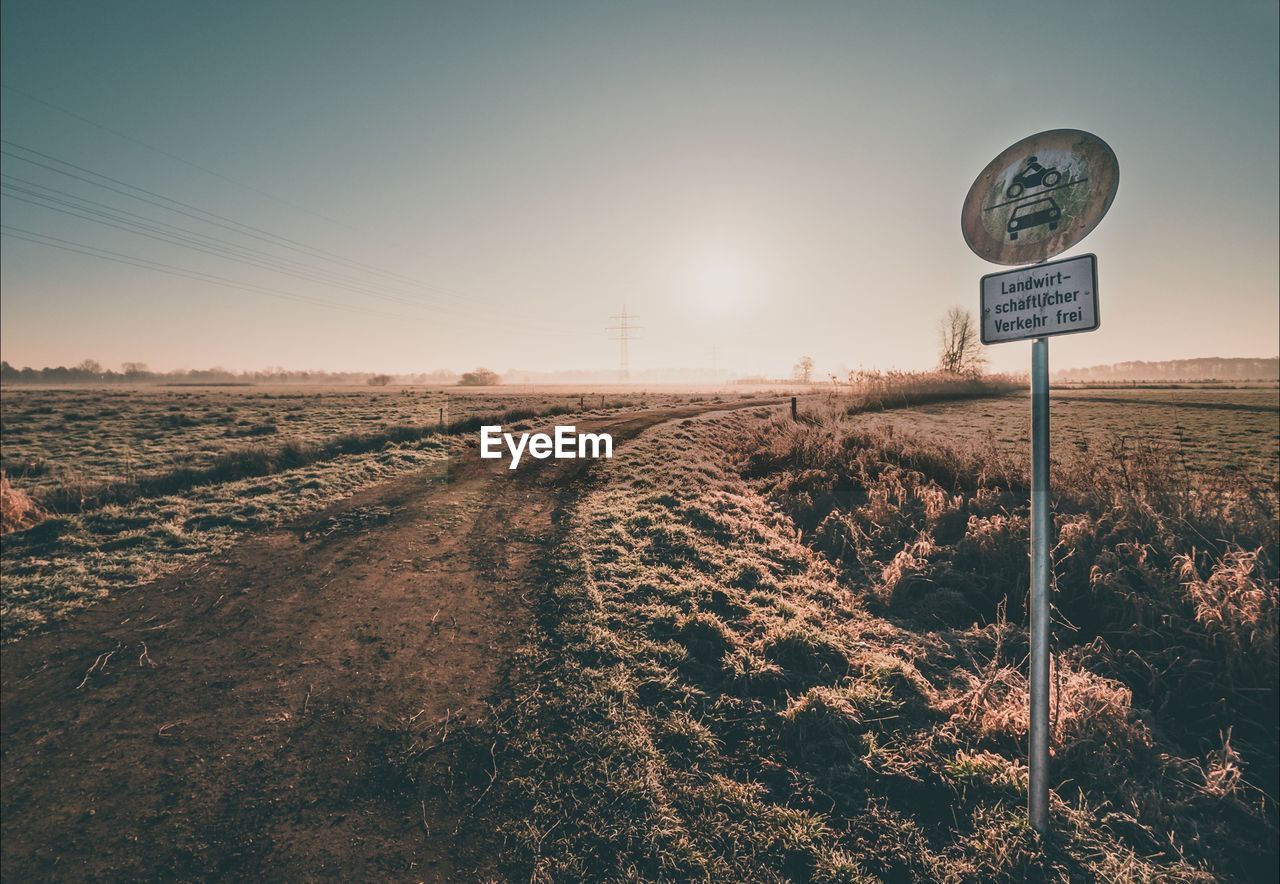 Road sign on land against sky