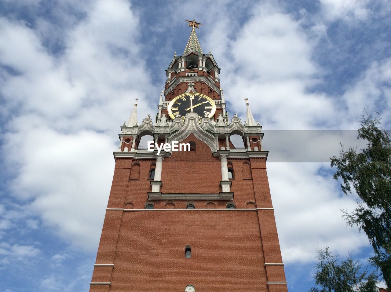 Low angle view of spasskaya tower against cloudy sky