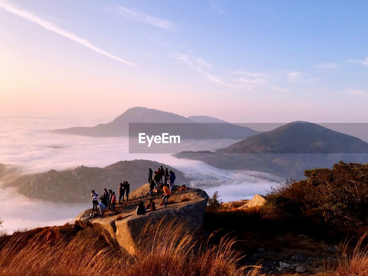 People by cloudscape on mountain during sunrise