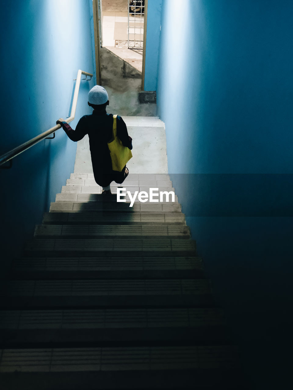 blue, light, staircase, steps and staircases, full length, architecture, one person, darkness, adult, built structure, indoors, men, green, railing, rear view, lifestyles, stairs, reflection, yellow, shadow, the way forward, sunlight, walking, day, snapshot