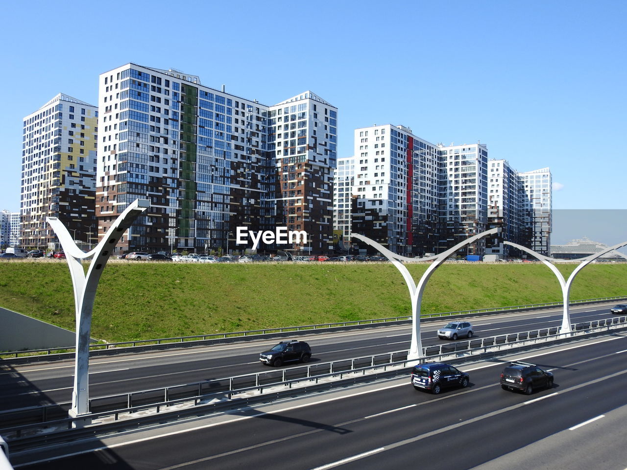 Vehicles on road by buildings against clear sky