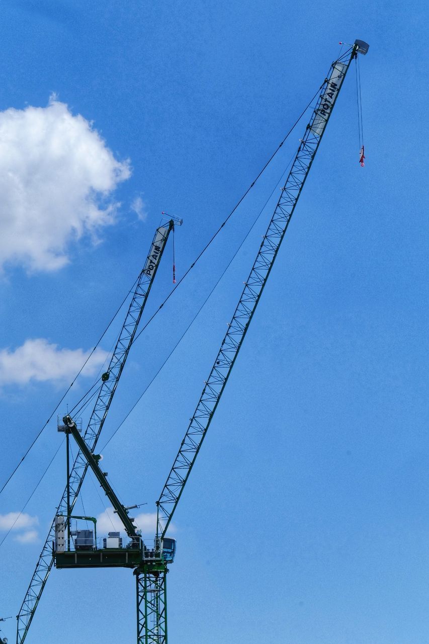 LOW ANGLE VIEW OF CRANES AGAINST BLUE SKY