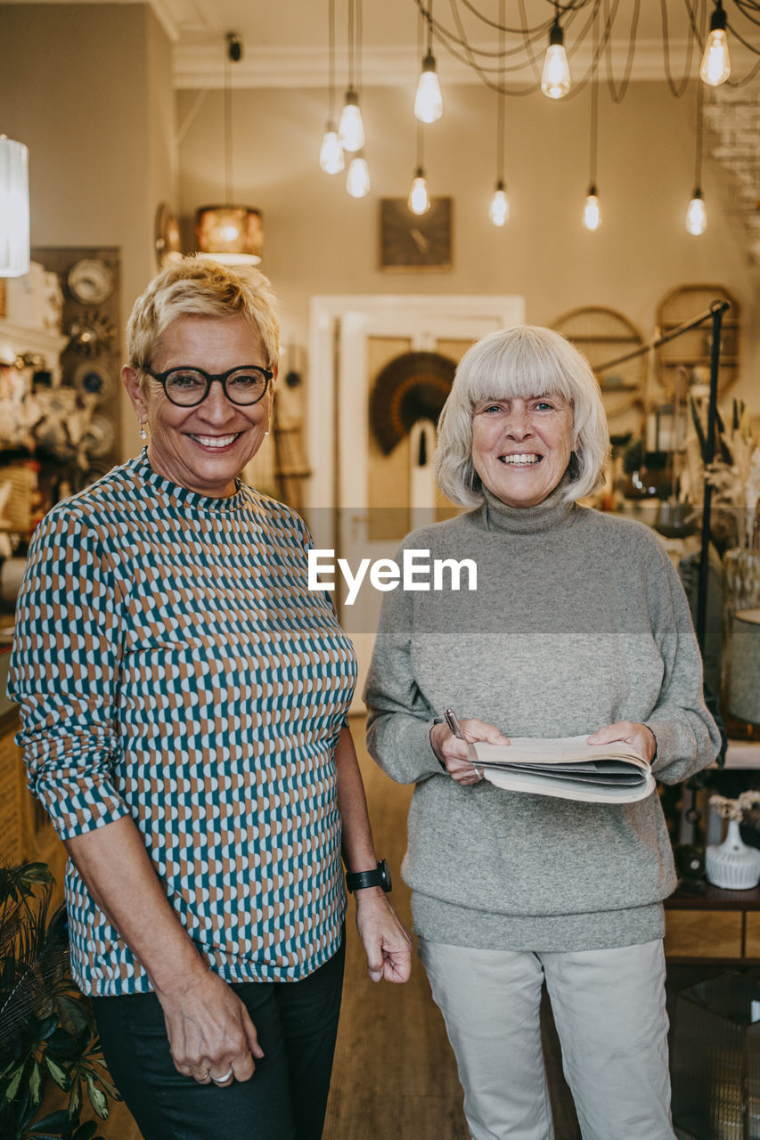 Happy senior female owners standing together at home decor shop