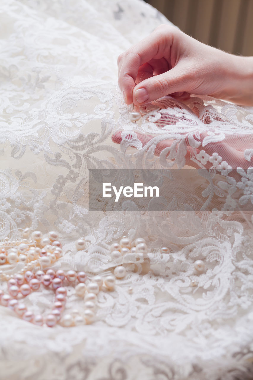 Cropped hands of woman stitching wedding dress