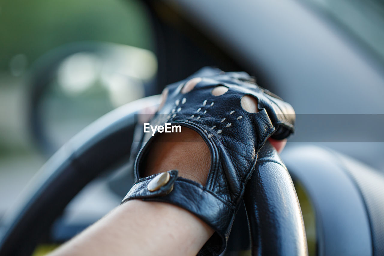 The driver's hands in leather gloves driving a moving car. woman holding