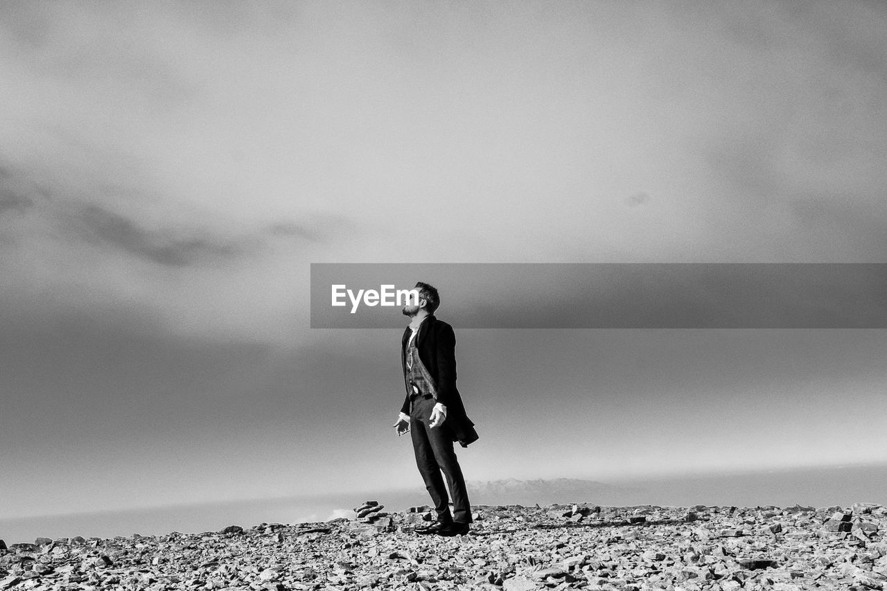 Full length of young man standing on beach against sky