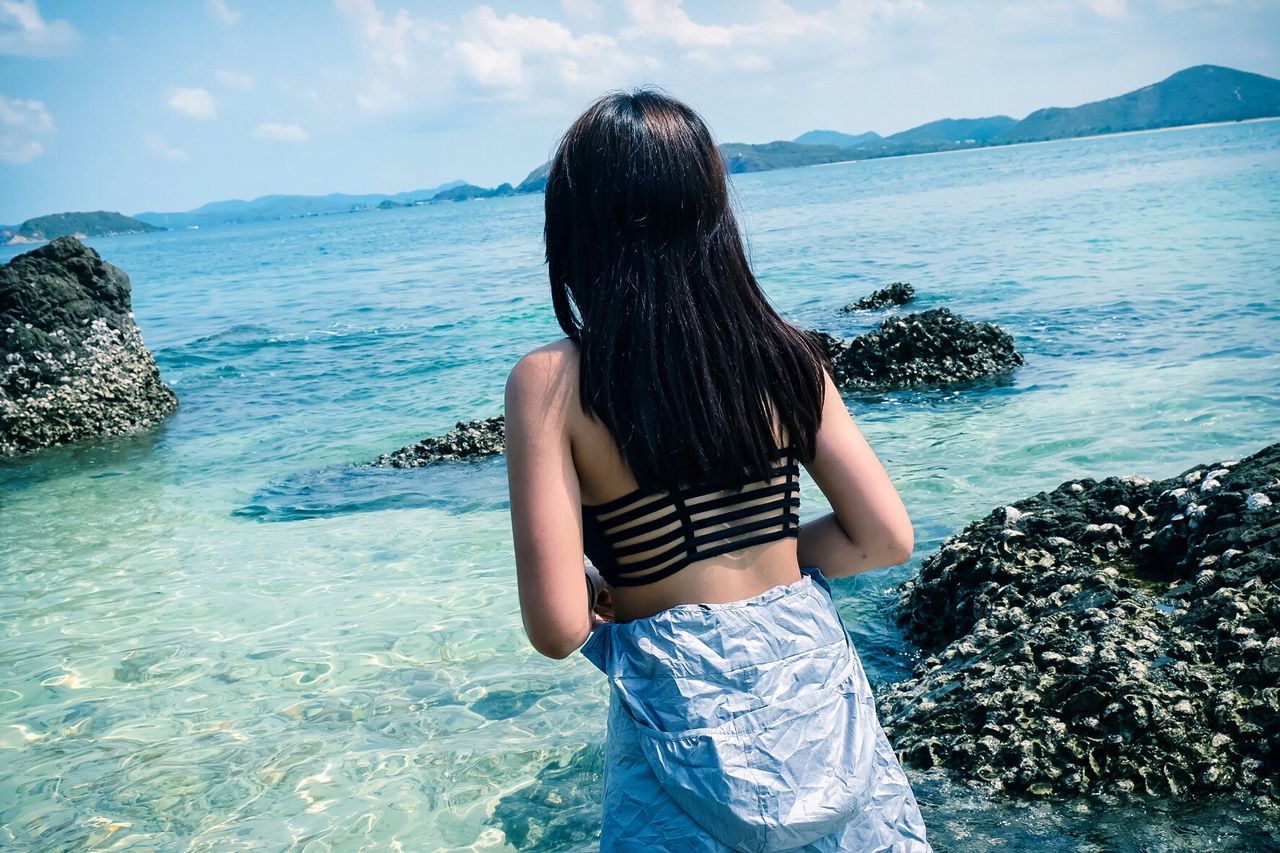 Rear view of woman standing in front of sea