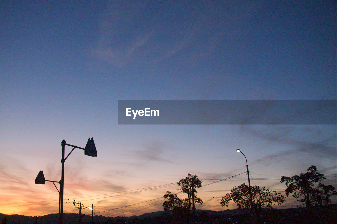 Low angle view of street lights against sky at sunset